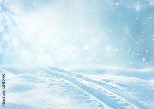 Winter snow blue background with snowdrifts, beautiful light, ski track and snow flakes on blue sky, beautiful bokeh circles, copy space.