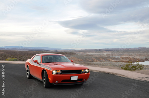 Fast red orange sport muscle car with burning lights in cloudy weather