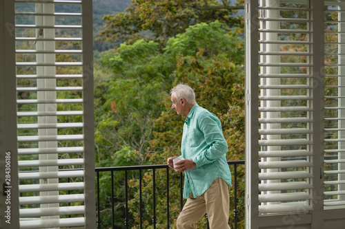 Wallpaper Mural Active senior man standing with coffee mug on the balcony Torontodigital.ca