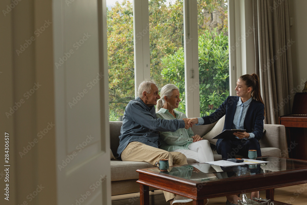 Obraz premium Active senior man shaking hands with real estate agent in living room