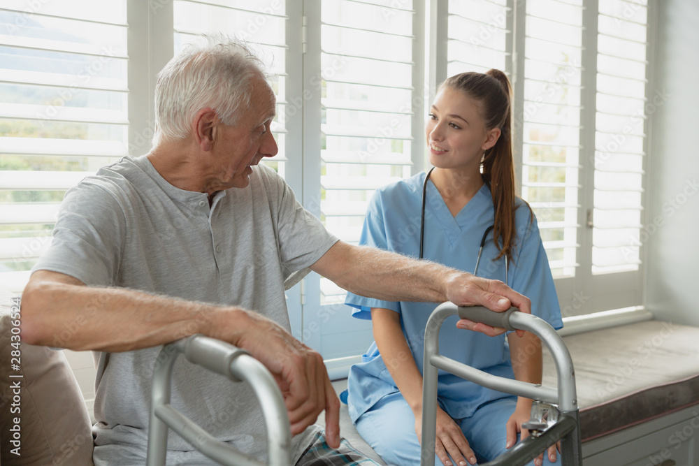 Fototapeta premium Female doctor interacting with active senior man on window seat