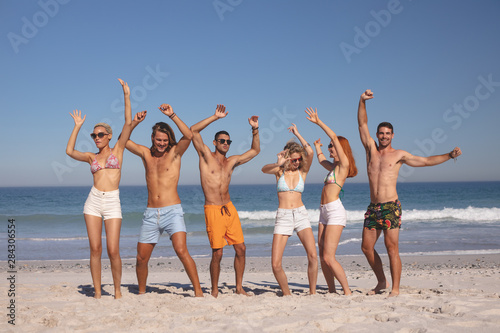 Group of friends dancing together on the beach