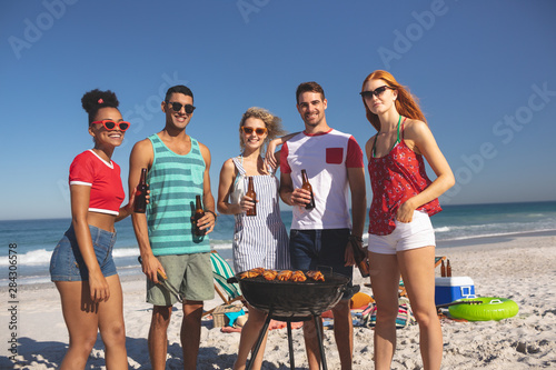 Group of friends having fun while preparing food on barbecue at beach