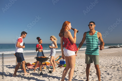 Group of friends having fun while having beer on the beach
