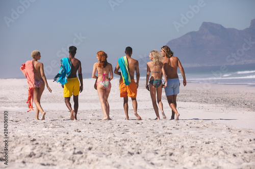 Group of friends walking together on the beach