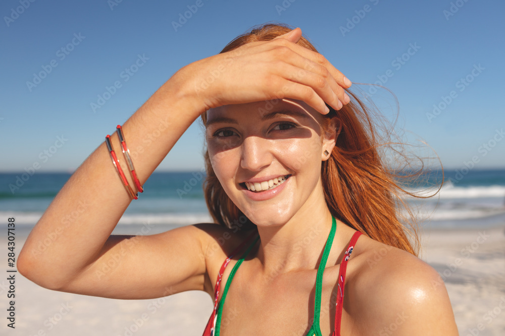Happy redhead woman standing on the beach