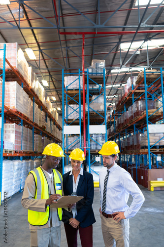 Diverse staffs working together on clipboard in warehouse