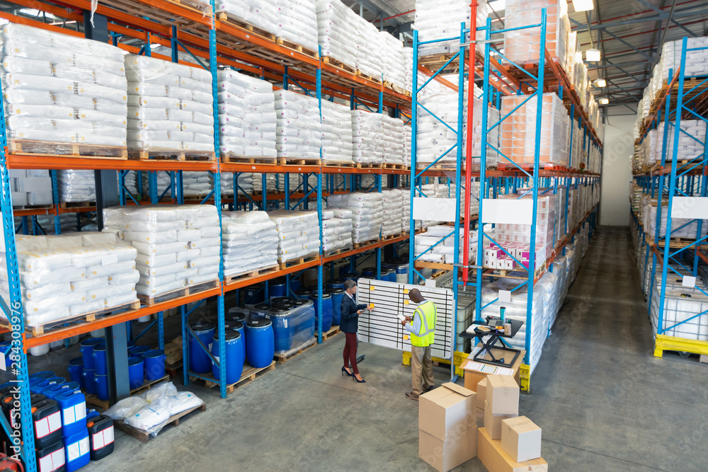 Warehouse staff discussing over whiteboard in warehouse Warehouse staff discussing over whiteboard in warehouse