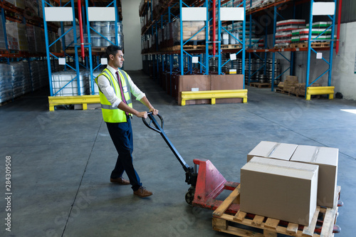 Male staff using pallet jack in warehouse photo