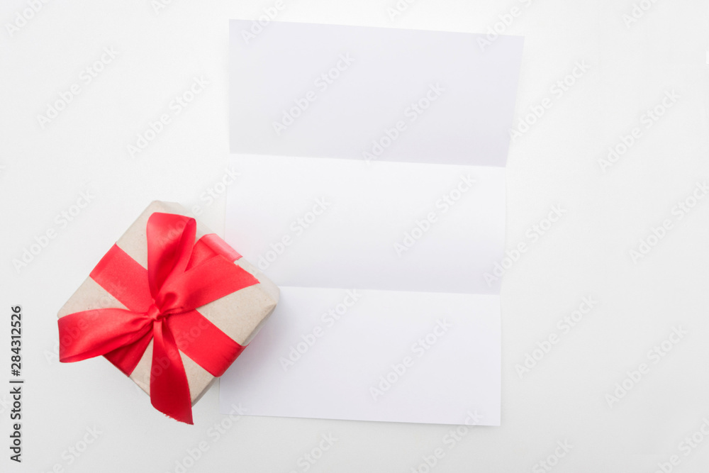 White desk, gift box with red ribbon, letter or white piece of paper, background, copy space, for recording, text, close up, top view