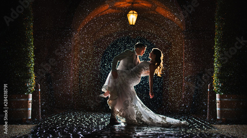 a bride and groom is dancing happily in the rain photo