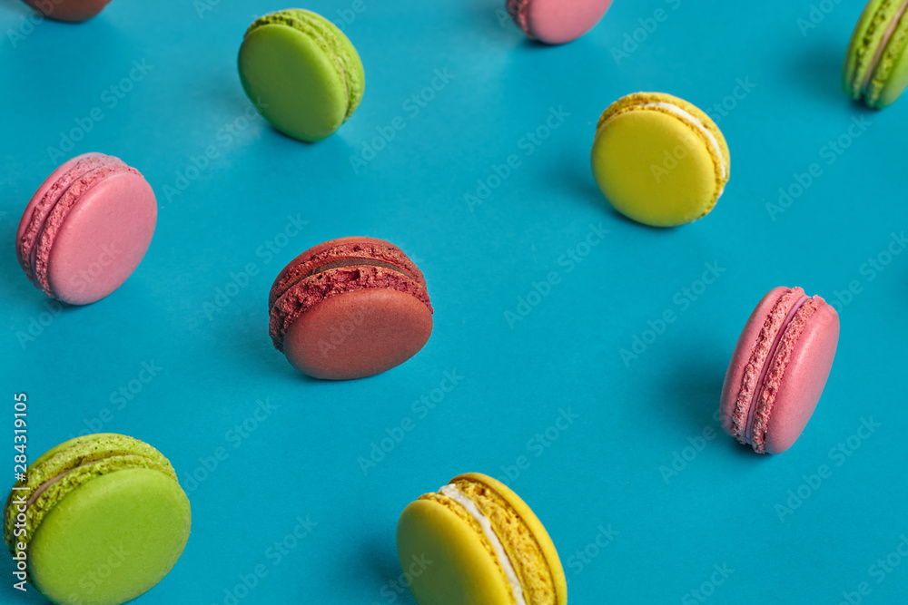 Fototapeta premium Colored macaron or macaroon, sweet meringue-based confection on blue background. Close-up, copy space.
