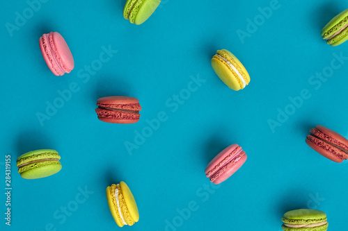 Colored macaron or macaroon, sweet meringue-based confection on blue background. Close-up, copy space.