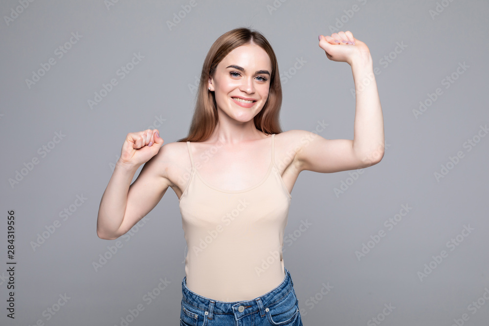 Used to success. Happy young woman in casual wear gesturing and keeping eyes closed while standing against grey background Used to success. Happy young woman in casual wear gesturing and keeping eyes closed while standing against grey background