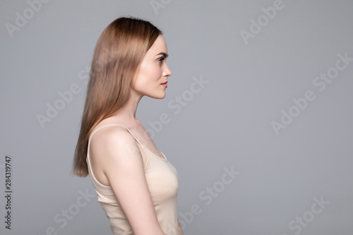 Close up side view of young woman standing isolated grey background