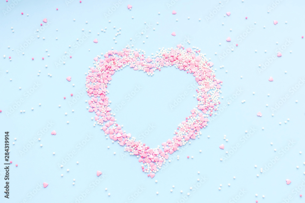 Valentine's Day. Heart made of pink confetti on blue background. Top view, flat lay composition. Copy space for text.
