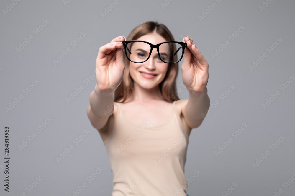 Glasses - optician showing eyewear. Closeup of glasses, with glasses and frame in focus. Woman on gray background. Glasses - optician showing eyewear. Closeup of glasses, with glasses and frame in focus. Woman on gray background.