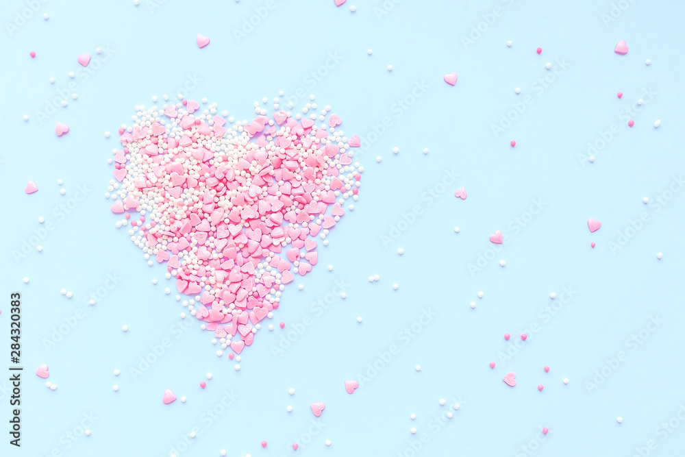 Valentine's Day. Heart made of pink confetti on blue background. Top view, flat lay composition. Copy space for text.
