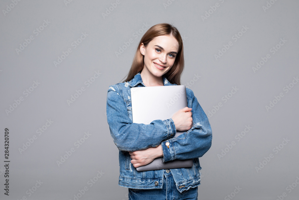 Young happy smiling woman in casual clothes holding laptop and sending email to her best friend isolated on gray background Young happy smiling woman in casual clothes holding laptop and sending email to her best friend isolated on gray background