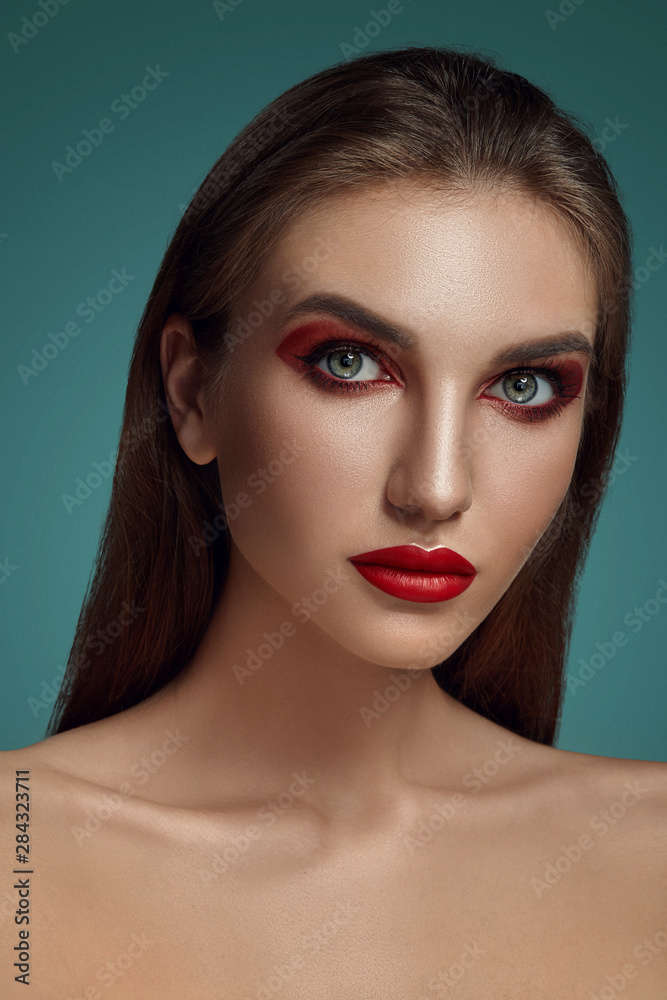 Close-up glamour portrait of a beautiful half-naked model with bright make-up posing over a gray background. Close-up glamour portrait of a beautiful half-naked model with bright make-up posing over a gray background.