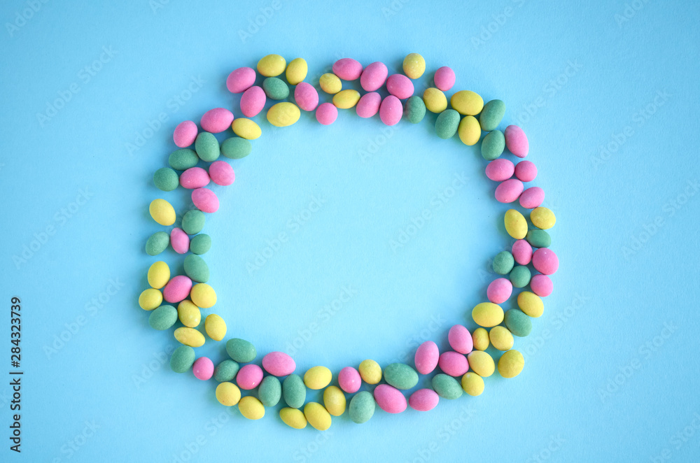 Colored sweets, peanut covered with glaze on blue background composition, round shape, frame. Colored sweets, peanut covered with glaze on blue background composition, round shape, frame.
