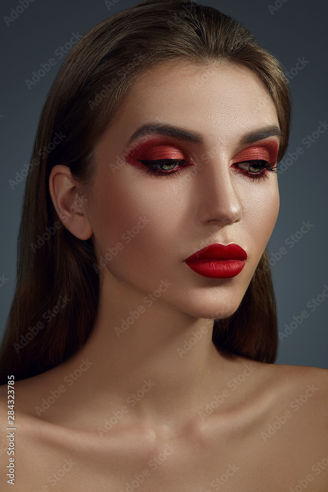 Close-up glamour portrait of a beautiful half-naked model with bright make-up posing over a gray background. Close-up glamour portrait of a beautiful half-naked model with bright make-up posing over a gray background.