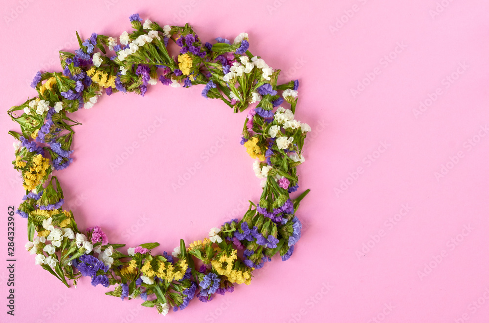 Colored flowers on pink background composition, circle shape. Flat lay