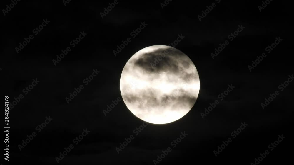 Full moon and clouds on a summer night sky. Moon With Clouds In The Night Sky. Full moon shining through the clouds Full moon and clouds on a summer night sky. Moon With Clouds In The Night Sky. Full moon shining through the clouds