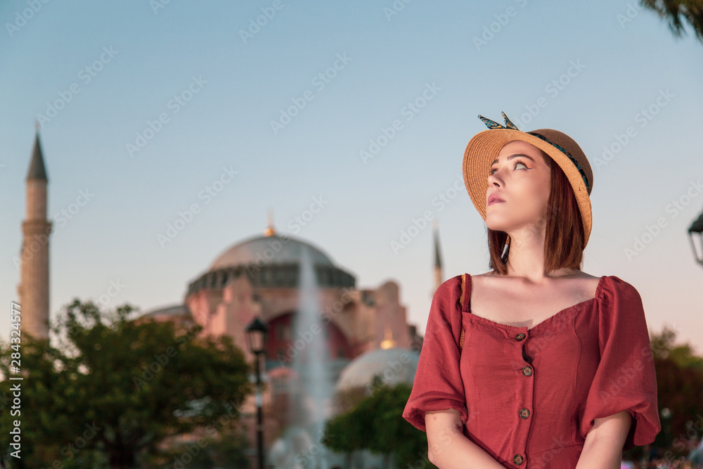 Beautiful girl with orange colored dress posing with Sultan Ahmet Mosque during sunset from Istanbul