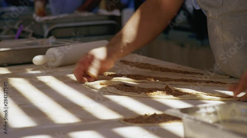 Turkish man working in a bakery making ispanakli fresh bread and preparing it on a table coated with white flour photo