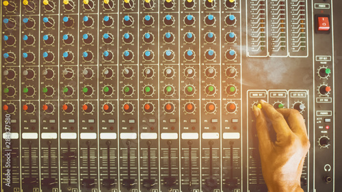 Man's hand and the control knob of the analog audio mixer. photo