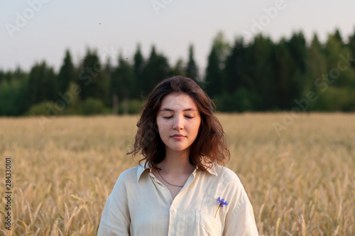 Young girl with closed eyes in a wheat field