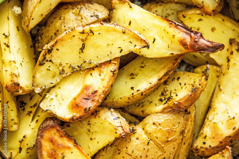 Oven baked potato in the oven with peel and spices in a baking dish. View from above. Potato wedges in peel, homemade lunch concept, dish with potatoes, baked potato recipe, Rustic potato