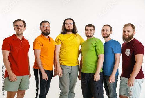 Young men weared in LGBT flag colors isolated on white background. Caucasian male models in shirts of red, orange, yellow, green, blue and purple. LGBT pride, human rights and choice concept.