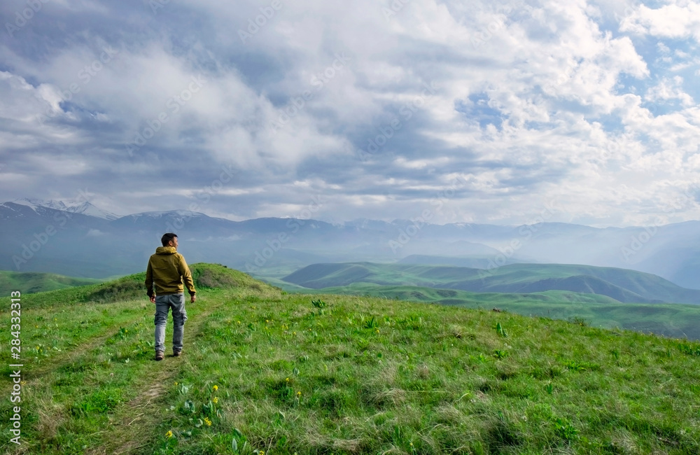 Beautiful landscape, man standing on the hill in front of mountains