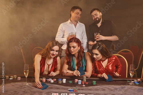 Group of a young wealthy friends are playing poker at a casino.