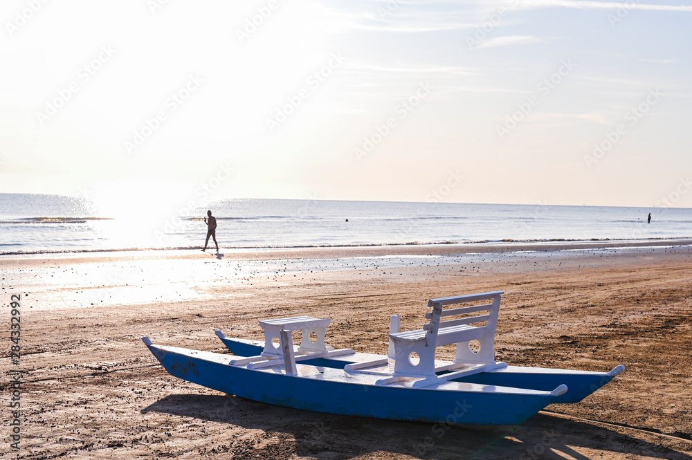 Catamaran with a white wooden seat by the sea. Sandy beach and sunny dawn. Beautiful horizon and sun flare. Catamaran with a white wooden seat by the sea. Sandy beach and sunny dawn. Beautiful horizon and sun flare.