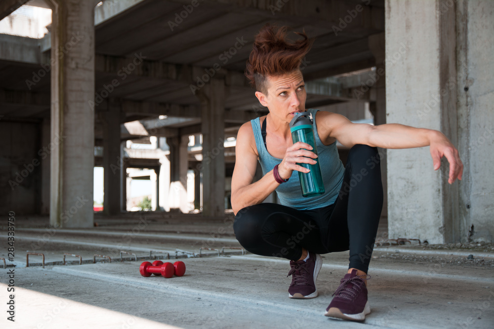 Fototapeta premium Beautiful fitness athlete woman drinking water after work out exercising