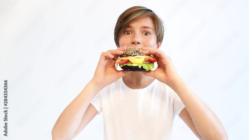 Beautiful teenager takes a bite of his sandwich. Fast food. Teenagers. Beautiful teenager takes a bite of his sandwich. Fast food. Teenagers.