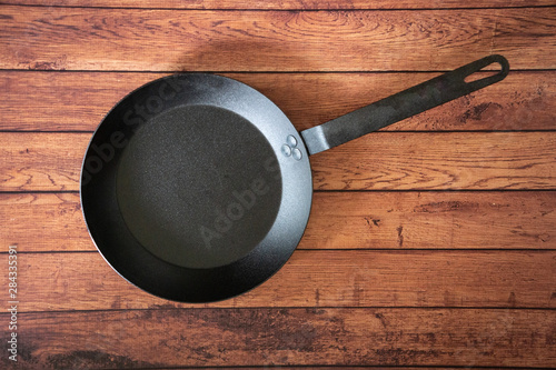 Isolate carbon steel skillet pan on a wooden background - overhead top view