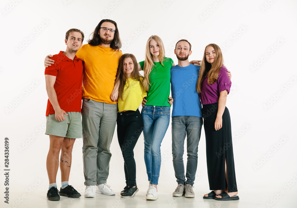 Obraz premium Young man and woman weared in LGBT flag colors on white background. Caucasian models in bright shirts. Look happy together, smiling and hugging. LGBT pride, human rights and choice concept.