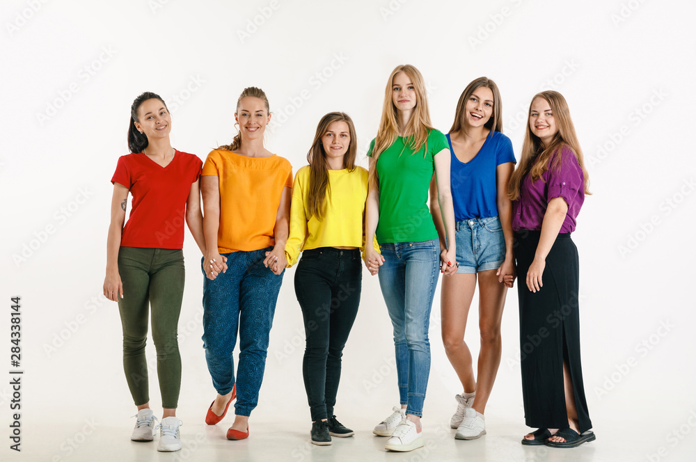 Obraz premium Young man and woman weared in LGBT flag colors on white background. Caucasian models in bright shirts. Look happy together, smiling and hugging. LGBT pride, human rights and choice concept.