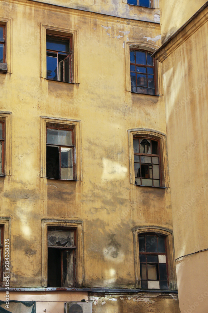 dilapidated facade of an old resettled abandoned apartment building with broken windows in the center of St. Petersburg, Russia