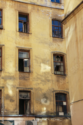 dilapidated facade of an old resettled abandoned apartment building with broken windows in the center of St. Petersburg, Russia