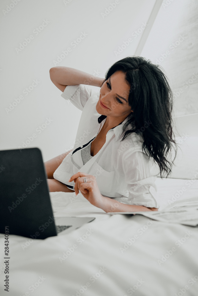 Girl in a bright room in bed looks at a laptop. Girl in a bright room in bed looks at a laptop.