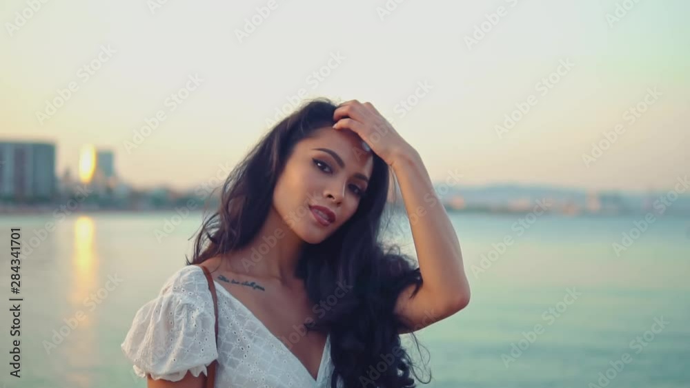 Beautiful girl in the white dress walking along the sea promenade. Elegance and tenderness concept Beautiful girl in the white dress walking along the sea promenade. Elegance and tenderness concept