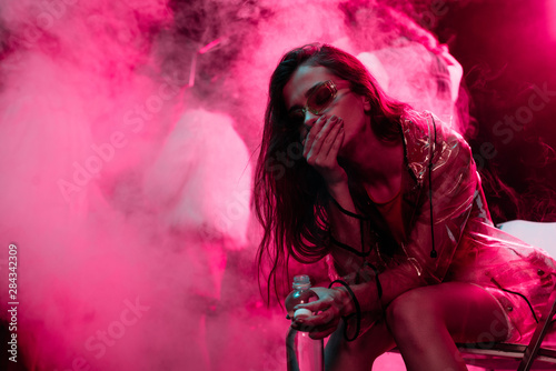 sick girl sitting with bottle of water in nightclub