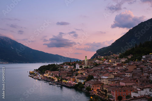 Panoramic view of night city Limone Sul Garda region Trento Lake Garda Italy. A popular resort town. Summer time of the year. Aerial view. City night lanterns, reflection of lamps.