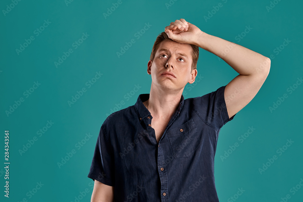 Close-up portrait of a ginger guy in navy t-shirt posing on blue background. Sincere emotions. Close-up portrait of a ginger guy in navy t-shirt posing on blue background. Sincere emotions.