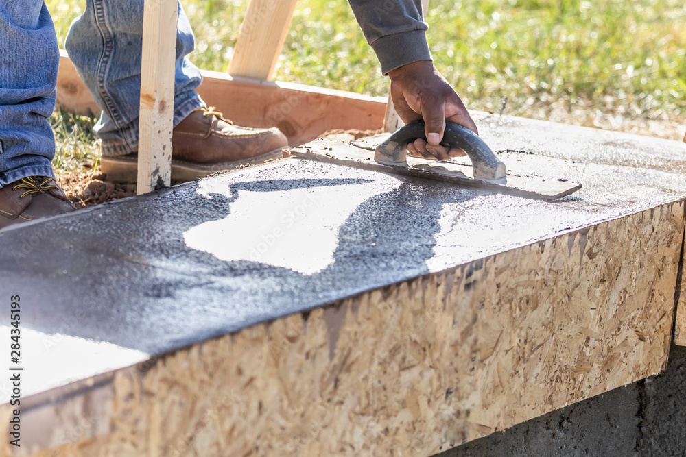 Construction Worker Using Wood Trowel On Wet Cement Forming Coping Around New Pool Construction Worker Using Wood Trowel On Wet Cement Forming Coping Around New Pool